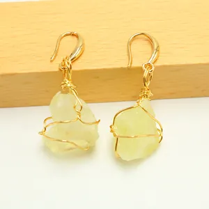 Detail of wire-wrapped earrings featuring irregular natural stones in a gold setting