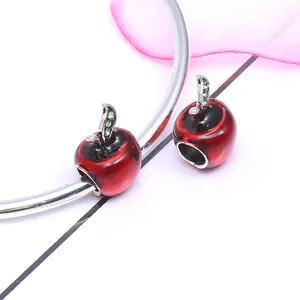 Red and black enamel apple charms with green crystals on silver snake chain bracelet
