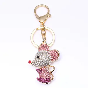 Détail d'un porte-clés souris doré orné de strass roses et blancs avec fermoir mousqueton