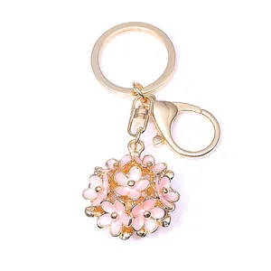 Vue détaillée du pendentif sphère dorée avec fleurs en émail rose pour sac à main