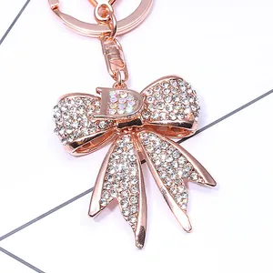 Porte-clés nœud en or rose avec lettre D en strass et fermoir mousqueton brillant