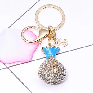 Porte-clés sac d'argent doré avec signe dollar, strass brillants et détails en émail bleu