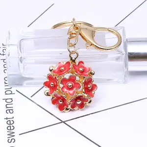 Porte-clés boule florale 3D rouge et doré suspendu à un flacon de parfum chic