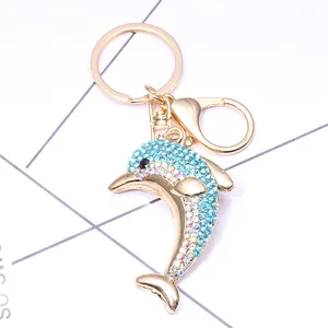 Détail d'un porte-clés dauphin doré avec strass bleus sur un fond géométrique