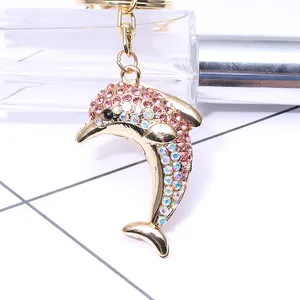 Porte-clés dauphin doré avec strass roses et fermoir mousqueton sur fond blanc