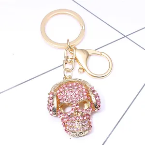 Pink rhinestone skull keychain with headphone detail on a gold metal lobster clasp base