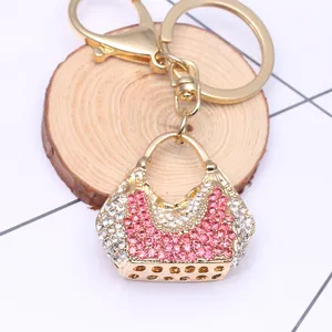 Golden alloy shell bag keychain with pink rhinestones and lobster clasp on wood