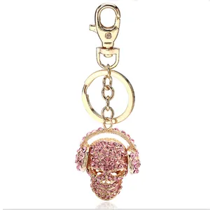 Pink rhinestone skull keychain with headphones on a golden alloy metal keyring