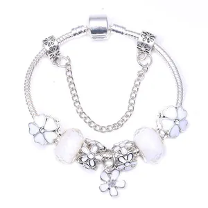 Silbernes Schlangenarmband mit weißen Emaille-Blumenanhängern und facettierten Perlen