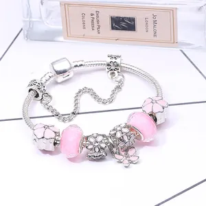 Detail eines rosa Blumen-Charm-Armbands mit Kirschblütenanhänger und Glasperlen