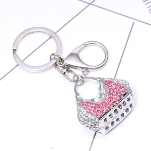 Detail of pink rhinestone handbag keychain with silver lobster clasp on grid background