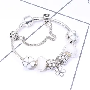 Silbernes Schlangenarmband mit weißen Emaille-Blumenanhängern und klaren Glasperlen