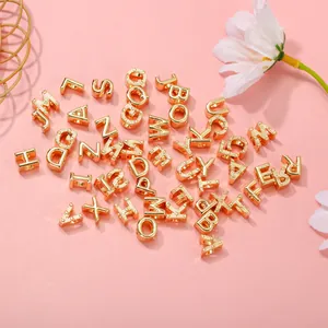 Perline dorate con lettere per creazione gioielli fai-da-te su sfondo rosa estetico
