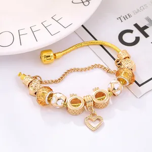 Golden snake chain bracelet with heart charms and amber glass beads on a magazine