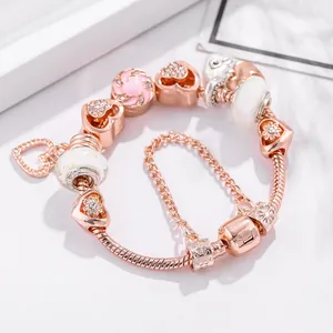 Rose gold crown bracelet with pink heart charms and sparkling crystals on marble surface
