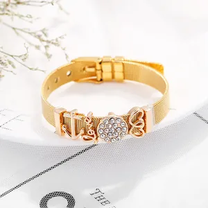 Gold mesh watch strap bracelet with anchor love and heart charms on white fabric