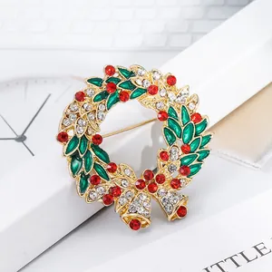 Christmas wreath brooch with colorful rhinestones and gold bells on a white background