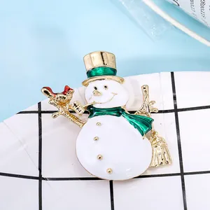 Charmante broche bonhomme de neige dorée avec émail coloré sur un plateau à carreaux