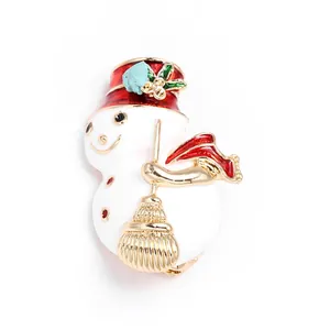 Détail d'une broche bonhomme de neige en émail festif avec chapeau rouge et balai doré