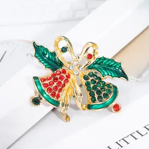 Festive Christmas bell brooch with crystals and gold bow on a clean white background