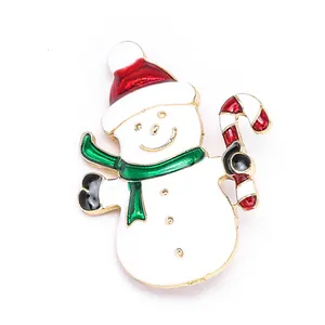 Détails d'une broche bonhomme de neige avec bonnet rouge et écharpe verte sur fond doré