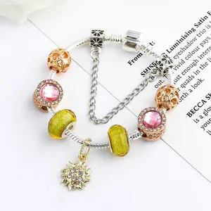 Pulsera de dijes de sol DIY con cristales rosas y cuentas de vidrio amarillas sobre fondo blanco