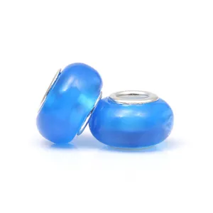 Détail macro de deux perles charm en acrylique bleu avec anneaux centraux en argent