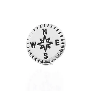 Détail macro d'un pendentif boussole en argent avec étoile et gravures directionnelles