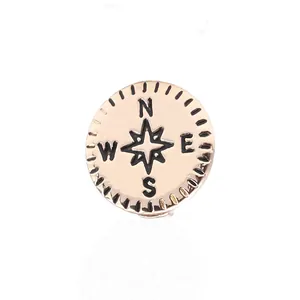 Vue macro d'un pendentif boussole or rose avec étoile gravée et repères de direction