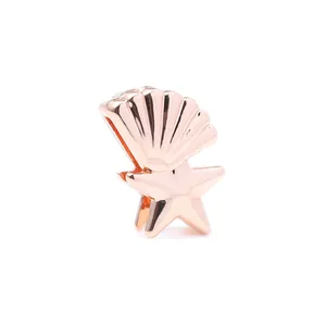 Détail macro d'un charm coquille et étoile de mer en or rose avec finition polie