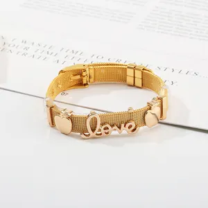 Golden stainless steel mesh bracelet with Love script and apple charms on magazine background
