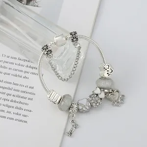 DIY zilveren bedelarmband met schattige pootafdrukken en bottenhangers aan een slangenketting