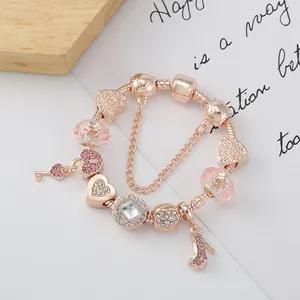 Roségold Armband mit rosa Kristallperlen und Herz-Schlüssel-Anhänger auf weißem Papier