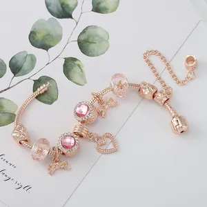 Roségoldenes Schlangenarmband mit rosa Kristallherz und Schleifenanhängern auf Karte