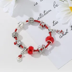 Dettaglio di bracciale natalizio intrecciato rosso con ciondoli Babbo Natale e bastoncini