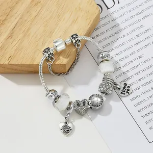 Bracelet à breloques argenté avec pendentifs cœur et cristaux sur socle en bois
