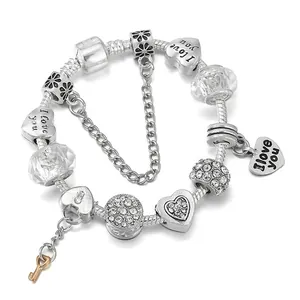 Bracelet à breloques argenté avec pendentifs cœurs, perles et breloque clé dorée