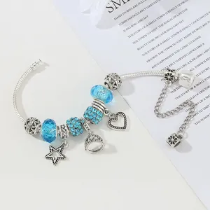 Bracciale con ciondoli a cuore e corona, perline di vetro blu e catena a serpente