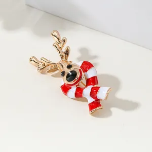 Golden Christmas reindeer brooch with red enamel scarf on minimalist cream background