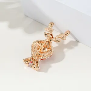 Golden metal reindeer brooch with red enamel details and safety pin back closure