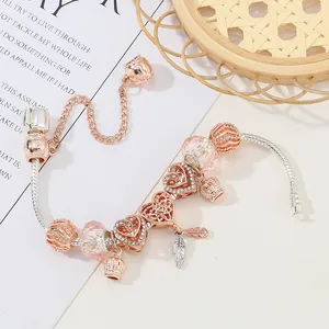 Roségouden bedelarmband met roze kristallen kralen, hartjes en een veerhanger