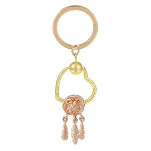 Détail du porte-clés doré en forme de cœur avec attrape-rêves bohème et pendentifs plumes