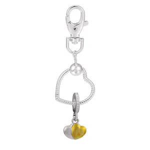 Détail d'un porte-clés en forme de cœur argenté avec pendentif jaune et fermoir mousqueton