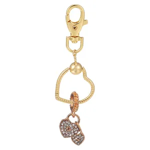 Porte-clés cœur doré orné de strass brillants et d'une perle orange sur fond blanc épuré