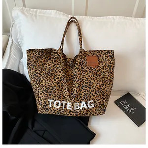Macro detail of leopard print canvas tote bag featuring white bold text and leather label