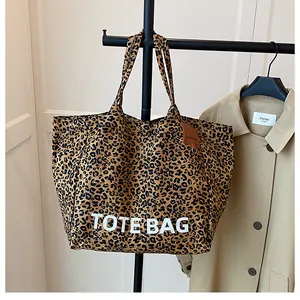 Detail of large leopard print tote bag hanging with a brown leather decorative tag