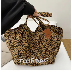 Detail view of large leopard print canvas tote bag with white TOTE BAG logo print