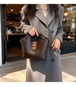 Dettaglio borsa in pelle intrecciata marrone scuro con chiusura girevole in metallo dorato