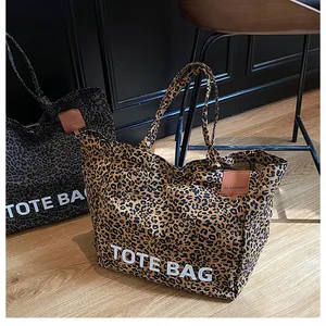 Detail of leopard print canvas tote bags in brown and grey with bold white lettering
