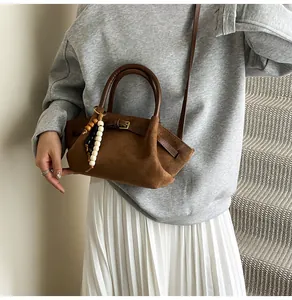 Detail of caramel frosted handbag with vintage leather straps and wooden bead charm accessory